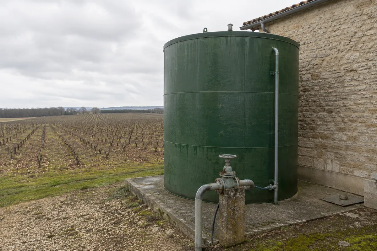 Cuve de stockage tampon des vinasses en extérieur près d&rsquo;un chai charentais, canalisation d&rsquo;alimentation